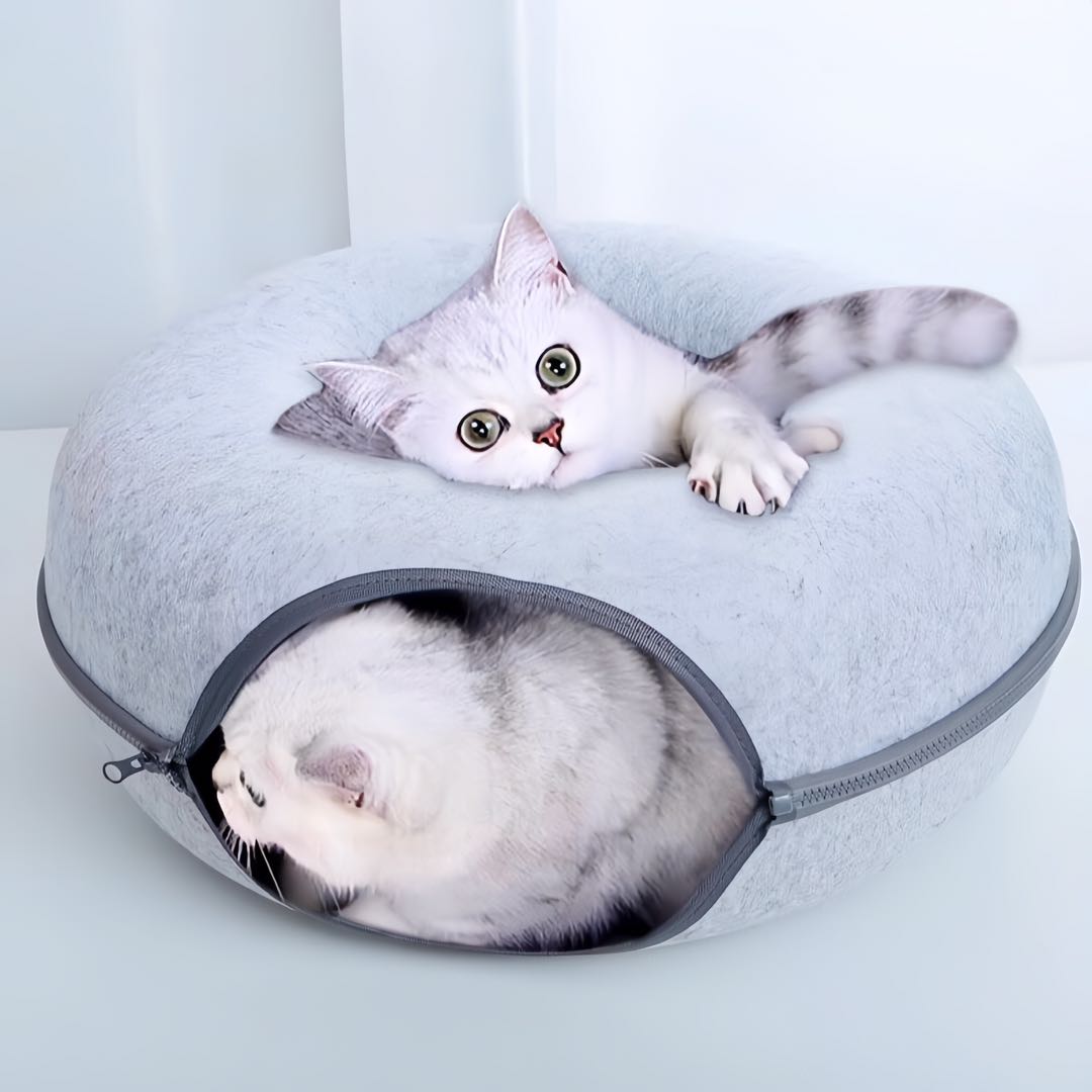 Two white cats resting on a large light grey colour donut shaped felt tunnel cat bed